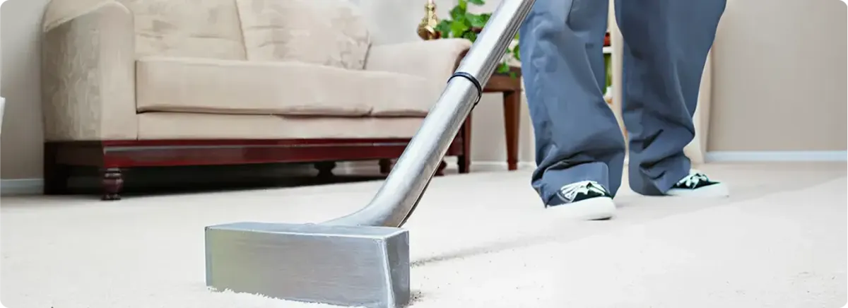 Carpet cleaning technician using a hot-water extraction wand on a light-colored carpet in a living room, Sacramento, CA.